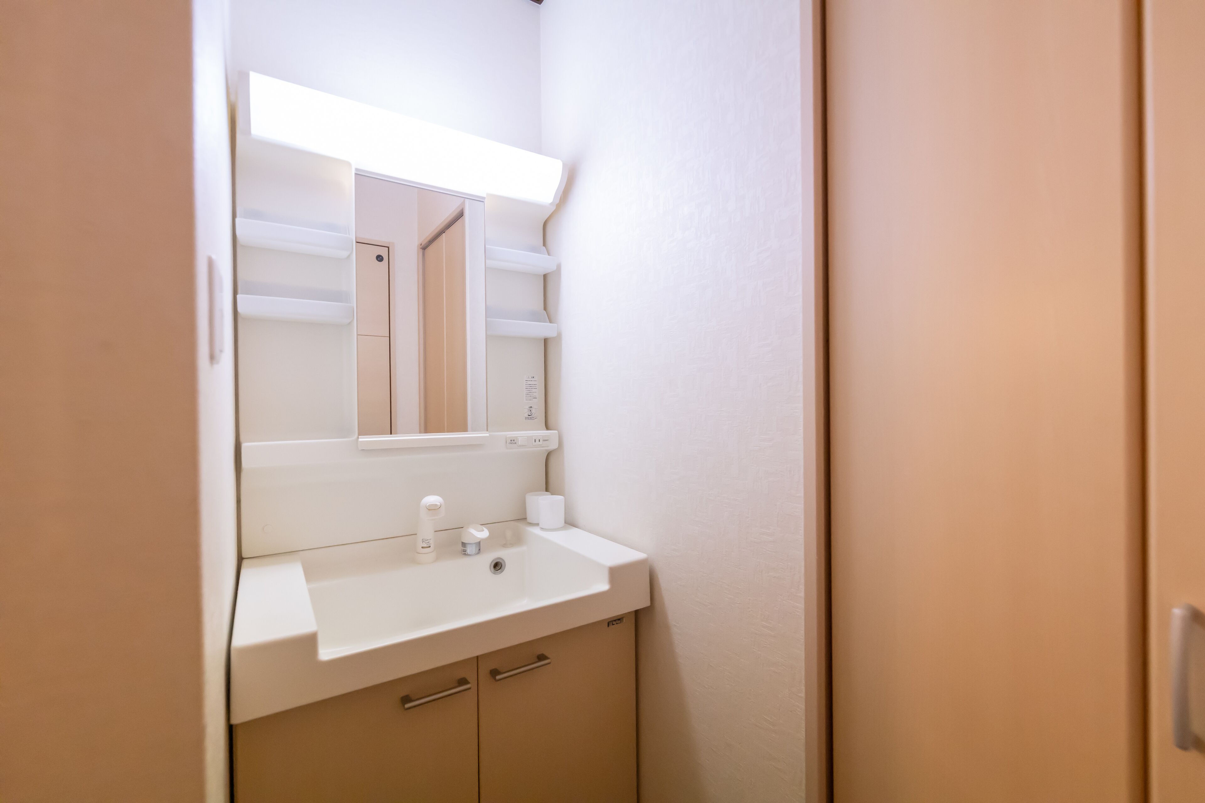 A bathroom with a white sink, mirror, and beige cabinets.