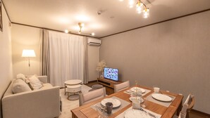 A modern living room with a dining area, a sofa, a TV, and a table set for four. - Ten-Cha House - Self-Check In Only (Osaka)