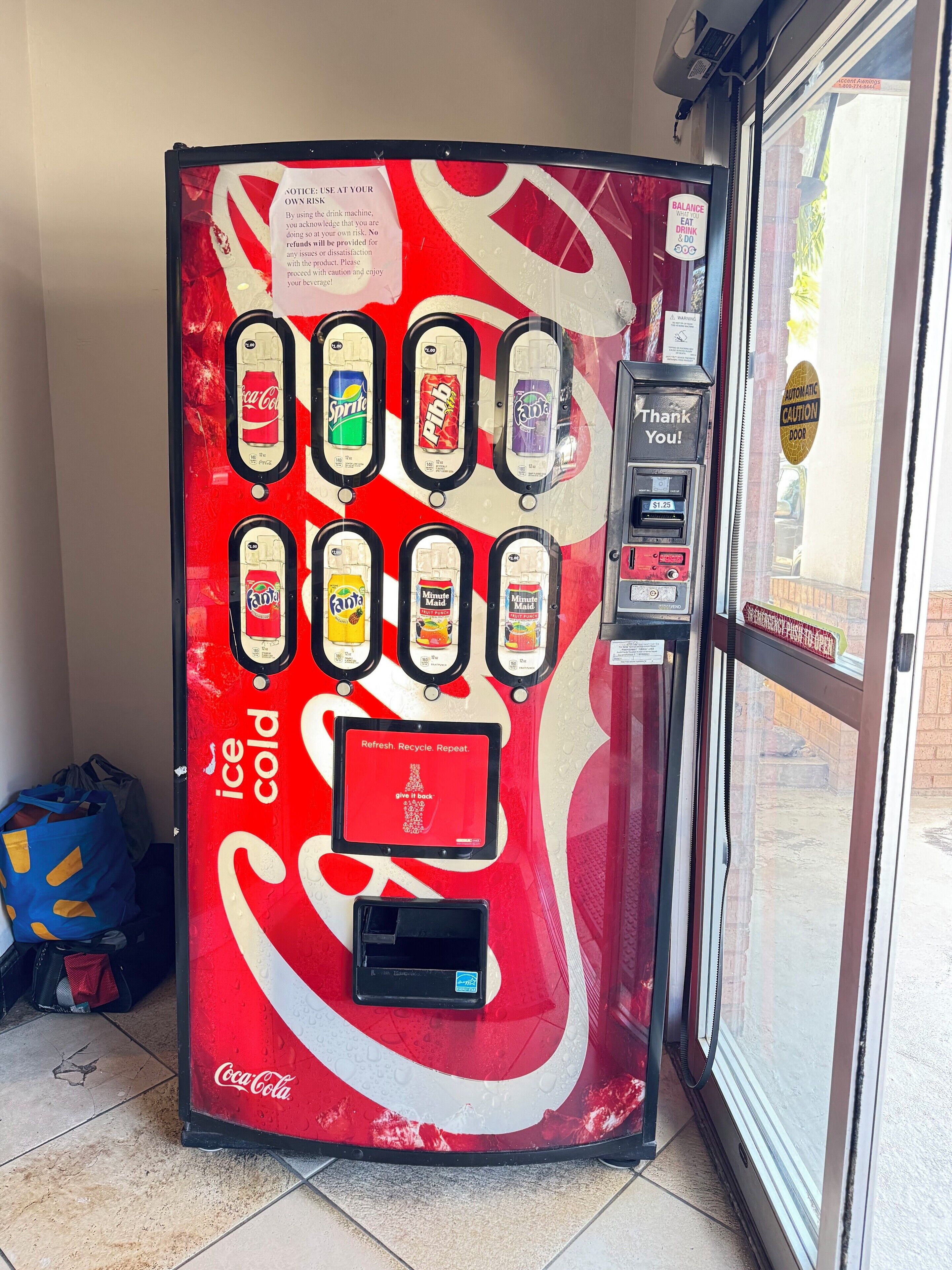 A red Coca-Cola branded vending machine with various drink options and a payment slot.