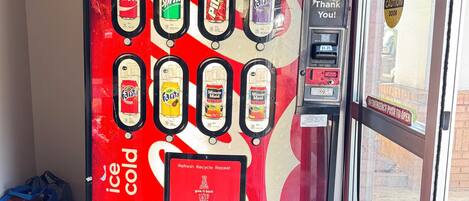 A red Coca-Cola branded vending machine with various drink options and a payment slot.