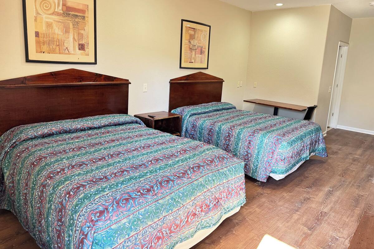 A bedroom with two beds, wooden headboards, and a small table.