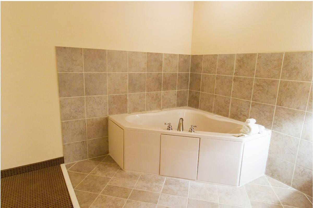 A corner bathroom with a freestanding bathtub, tiled walls, and a shower area.