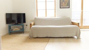 A living room with a sofa, a TV on a stand, and a window with a view.