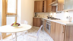 A modern kitchen with wooden cabinets, a gas stove, and a dining area with a table and chairs.