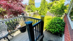 A wooden deck with a black railing, a potted plant, and a small table. - Top Floor Apartment, Workspace, Near Downtown, ONP (Port Angeles)