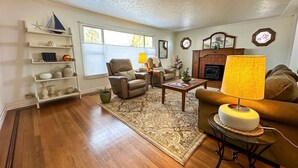 A living room with hardwood flooring, a coffee table, a sofa, a lamp, and a fireplace. - Top Floor Apartment, Workspace, Near Downtown, ONP (Port Angeles)