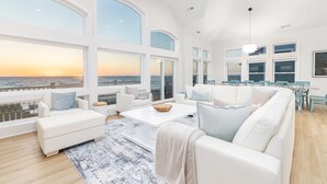 A spacious living room with large windows, a ceiling fan, and a dining area with a table and chairs. - 🌊 Ultra-Luxury OCEANFRONT | Private Heated Pool🏖️Hot Tub & Unmatched Views! (Corolla)