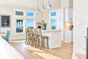 A modern kitchen with a central island, white cabinetry, and a view of the sea. - 🌊 Ultra-Luxury OCEANFRONT | Private Heated Pool🏖️Hot Tub & Unmatched Views! (Corolla)