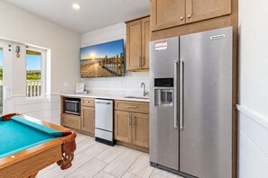 A modern kitchen with wooden cabinets, a stainless steel refrigerator, a microwave, and a built-in water dispenser. - 🌊 Ultra-Luxury OCEANFRONT | Private Heated Pool🏖️Hot Tub & Unmatched Views! (Corolla)