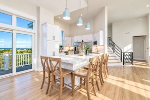 A spacious kitchen with a large island, white cabinetry, and a view to the outside. - 🌊 Ultra-Luxury OCEANFRONT | Private Heated Pool🏖️Hot Tub & Unmatched Views! (Corolla)