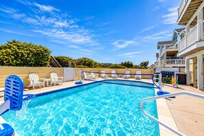 A swimming pool with clear blue water, surrounded by white lounge chairs and a wooden deck. - 🌊 Ultra-Luxury OCEANFRONT | Private Heated Pool🏖️Hot Tub & Unmatched Views! (Corolla)