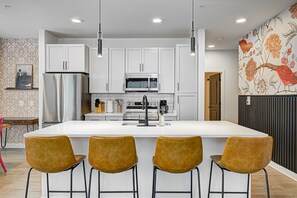 A modern kitchen with white cabinets, stainless steel appliances, and a central island with bar stools.