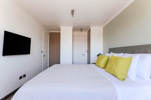 Camera d'albergo con un letto grande, una TV a schermo piatto montata a parete e una porta che dà su un'altra stanza.
