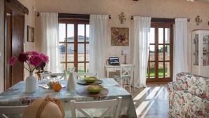 Un coin repas avec une table dressée pour deux personnes, un vase de fleurs et un ordinateur portable posé sur la table.