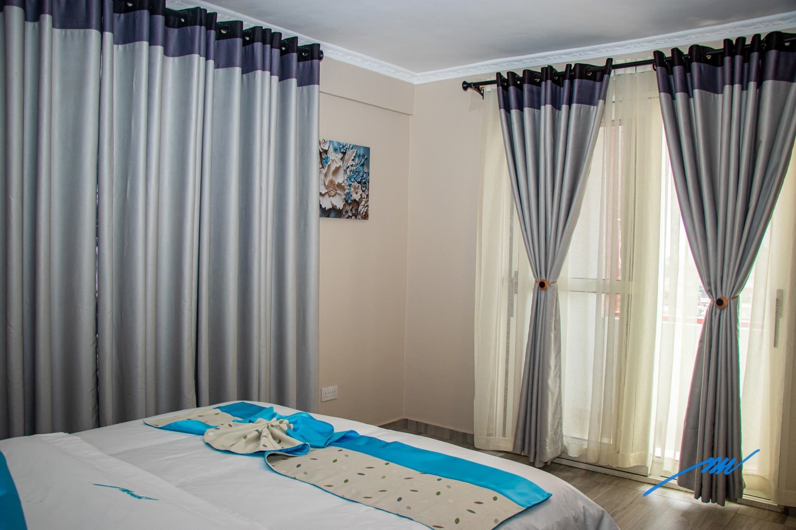 Una habitación de hotel con cama, cortinas y un cuadro en la pared.