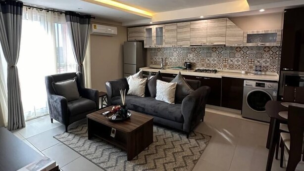 A modern living room with a sofa, coffee table, and a dining area.