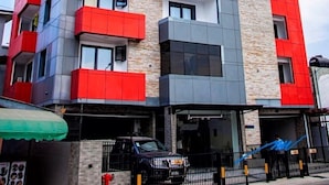 A multi-story hotel with a modern design, featuring balconies on each floor and a prominent logo on the facade.