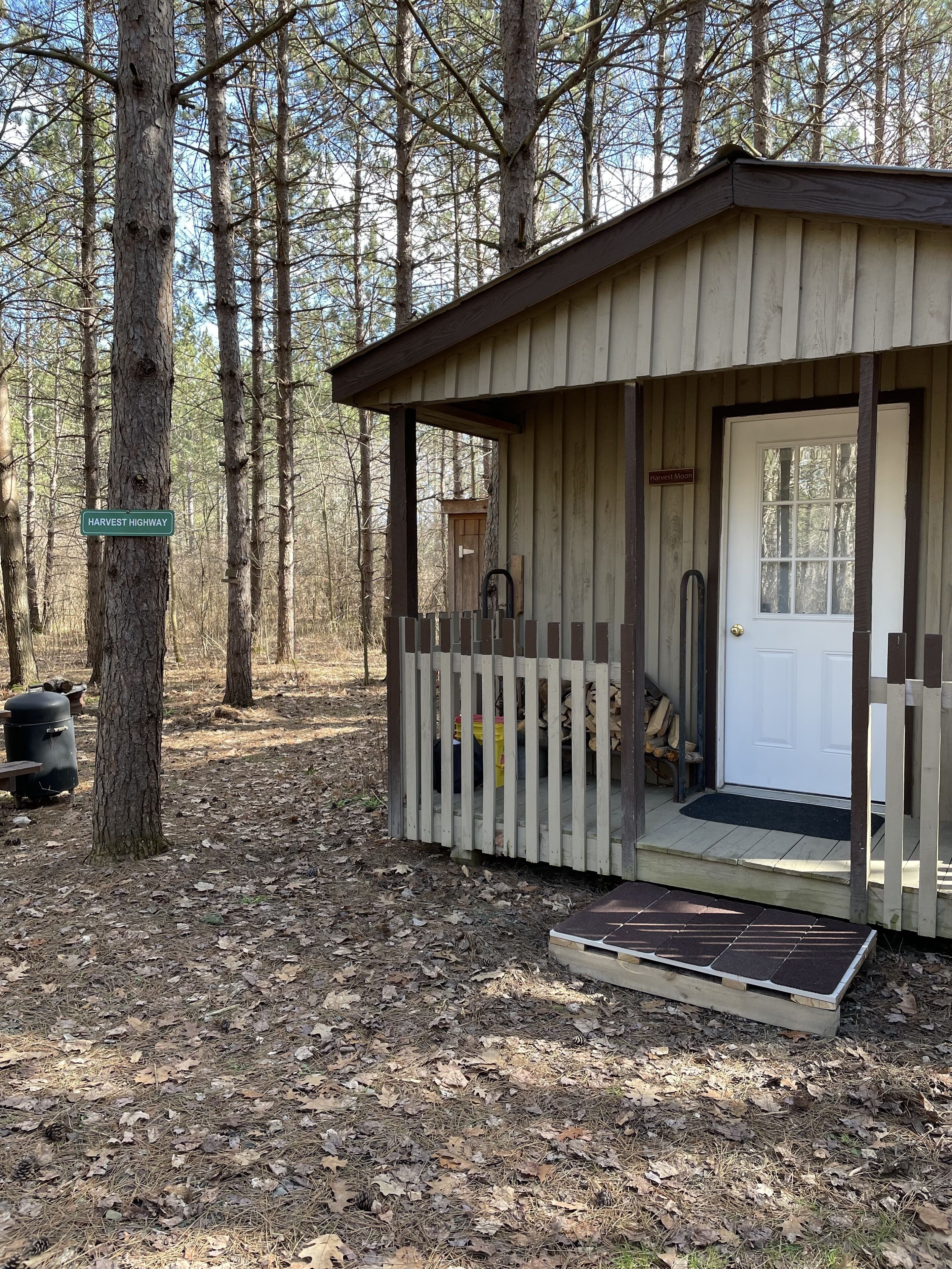 A rustic cabin with a wooden porch, a door, and a small step leading to the entrance.