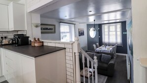 A modern kitchen with white cabinets, a black countertop, and a dining area with a table and chairs. - Rock Hollow (Halifax)