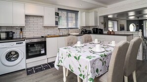 A compact kitchen with white cabinetry, a dining area with a table set for four, and a washing machine. - Rock Hollow (Halifax)