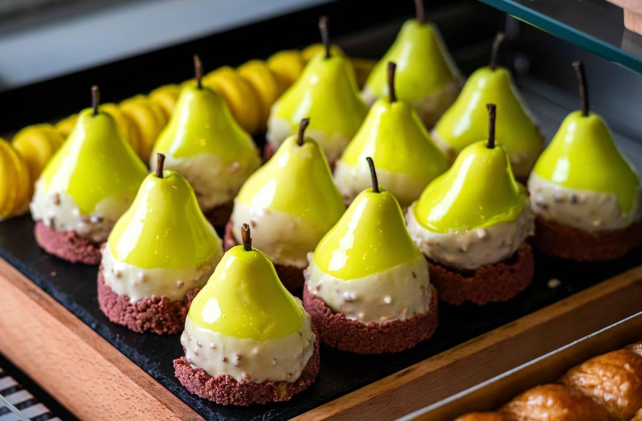 A tray of desserts with pear-shaped cakes on a black slate.