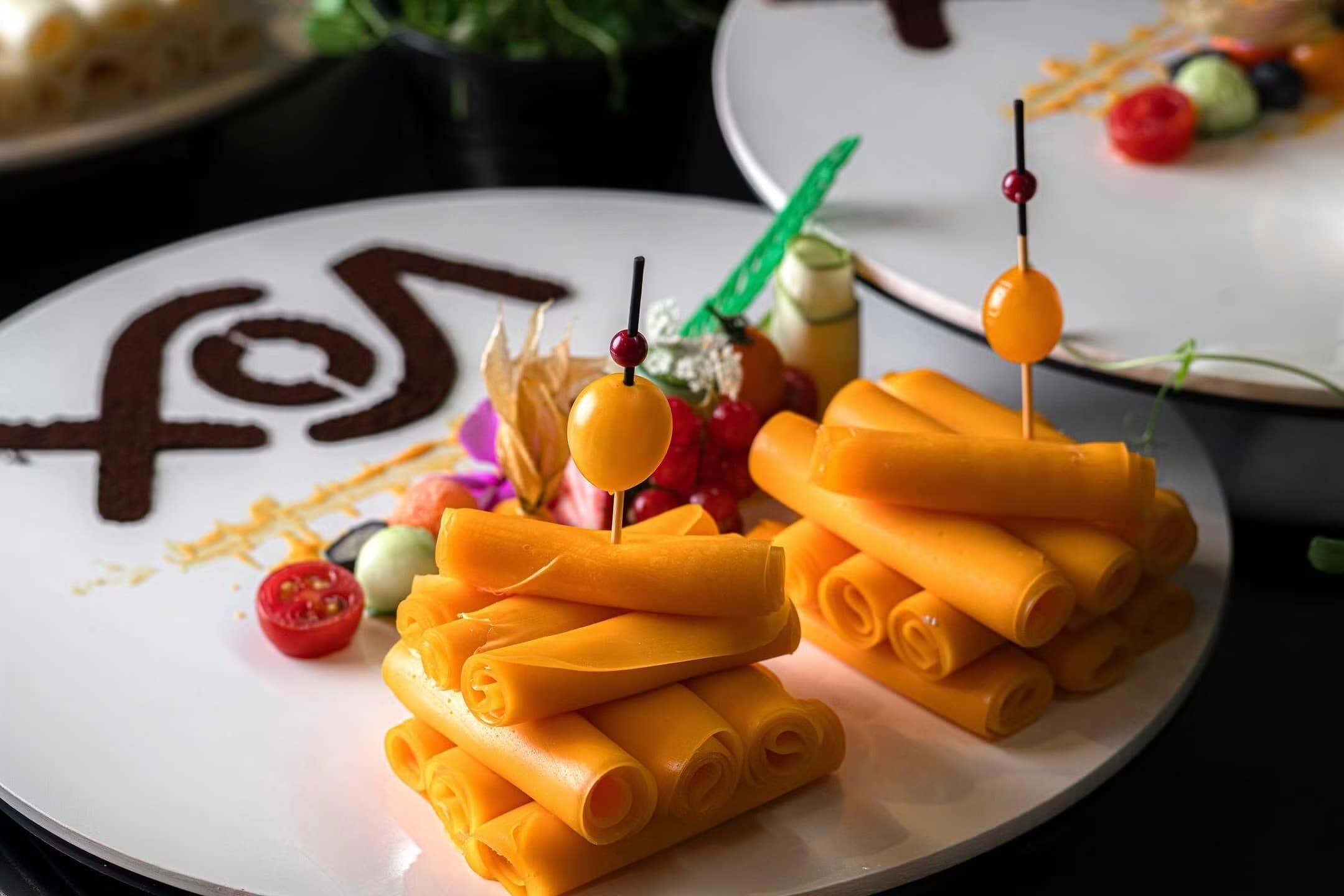 Une assiette de pâtes enroulées, garnie de tomates cerises et de brochettes.