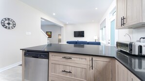 A modern kitchen with a dishwasher, wooden cabinets, a flat-screen TV, and a toaster. - TownHome In Ottawa! (Ottawa)