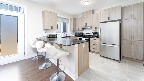 A modern kitchen with a central island, stainless steel appliances, and light wood cabinets. - TownHome In Ottawa! (Ottawa)