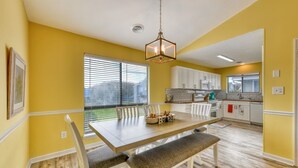 Une cuisine lumineuse avec des meubles blancs, une table à manger en bois et un banc.