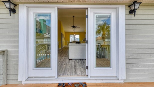 Une maison avec une porte-fenêtre coulissante, une terrasse en bois et un paillasson.