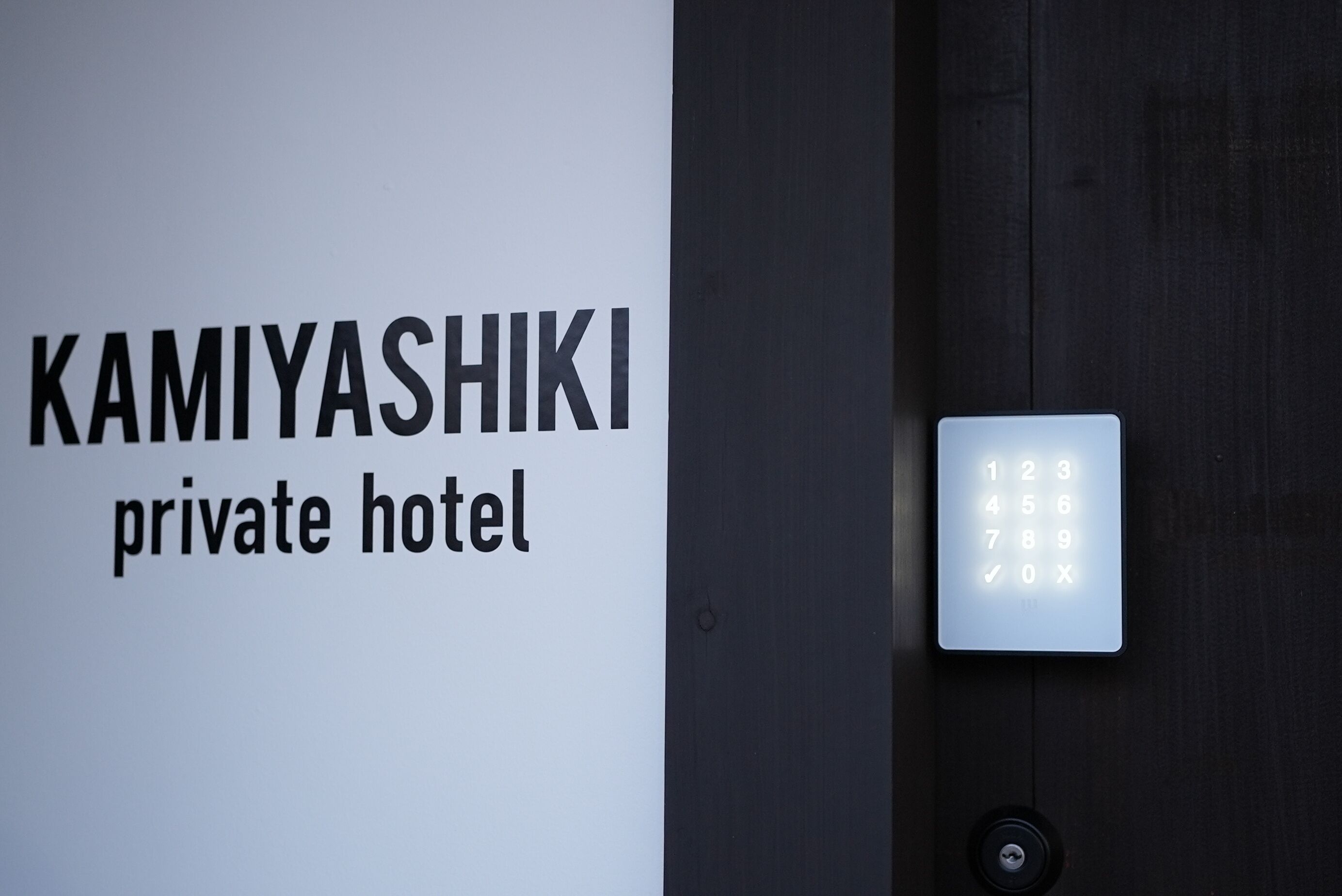 A sign for "KAMIYASHIKI private hotel" with a keypad lock.