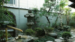 Un jardí japonès tradicional amb un fanal de pedra, bambú i diferents plantes.