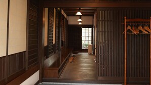 Un interior japonès tradicional amb portes corredisses de fusta, una banca de fusta i un penjador de roba.