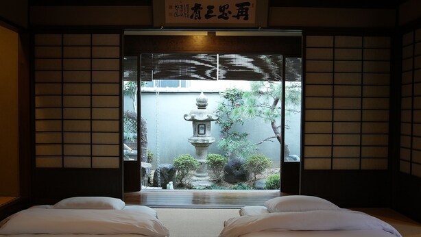 Habitació japonesa tradicional amb terra de tatami, un panell shoji i vista a un jardí amb un fanal de pedra.
