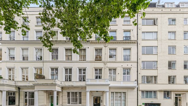 A row of townhouses with a central entrance, a small outdoor seating area, and a parked car. - The Paddington Rooms (London)