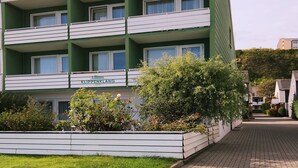 A multi-story hotel with balconies, a green facade, and a sign reading "Klippengl". - Hotel Klippenklang (Helgoland)