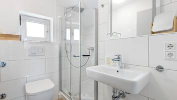Une salle de bain moderne avec une douche à parois de verre, un lavabo blanc et des toilettes.