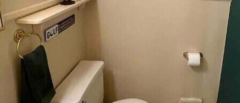 Une petite salle de bain avec des toilettes, un lavabo et des tableaux encadrés accrochés au mur.