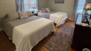 Habitació amb dos llits, un ventilador de sostre i una catifes.