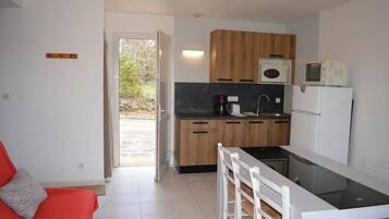 A compact kitchen with wooden cabinets, a black countertop, and a white refrigerator.
