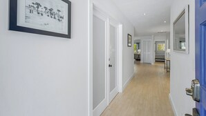 A hallway with white walls, a framed picture, and a blue door.