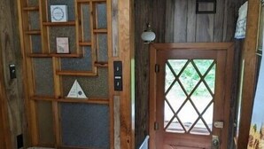 Ein rustikales Holzinnere mit einer eingebauten Bank, einer Holztür mit einem rautenförmigen Fenster und einem Heizkörper in der Nähe der Tür.