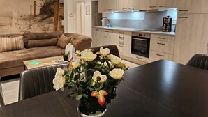 Uma sala de estar moderna com uma mesa de jantar de madeira escura, um sofá marrom e um quadro grande na parede.