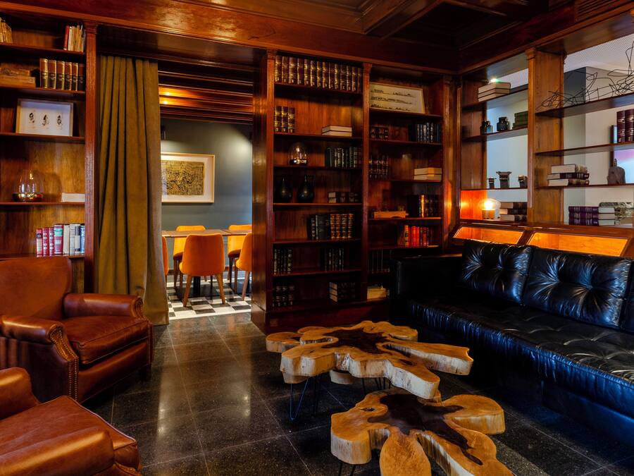 A library with leather furniture, bookshelves, and a checkered floor.