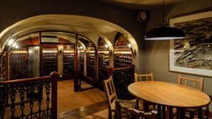 Una bodega con techos abovedados y una mesa redonda de madera con sillas.