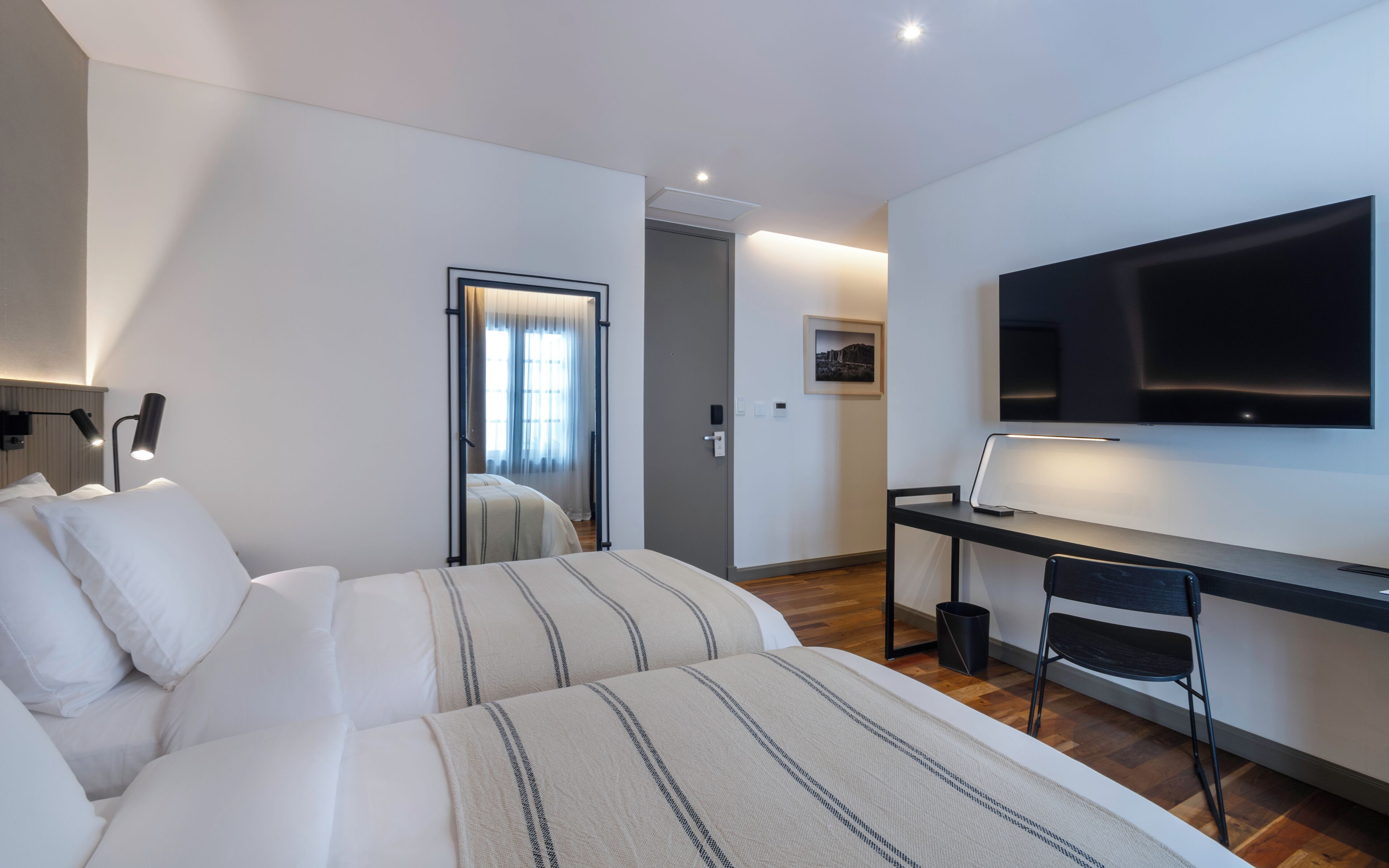 Une chambre d’hôtel comprenant un lit, un bureau avec une chaise, une télévision et une porte donnant accès à une salle de bain.
