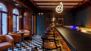 Un área de bar con paneles de madera, suelo de cuadros y sillones de cuero.