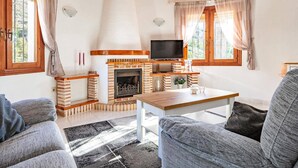 Ett mysigt vardagsrum med en öppen spis, en tv och bekväma sittplatser.