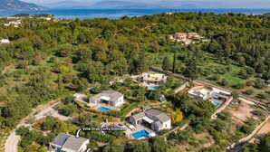 Villa Oras Corfu Dioni, featuring multiple modern houses with swimming pools, surrounded by lush greenery and a scenic view of the sea. - Villa Oras Corfu Dionisos by Villa Plus (Ionian Islands)