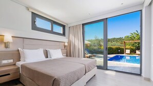 A modern hotel room with a large bed, a desk, and a view of a swimming pool and garden.